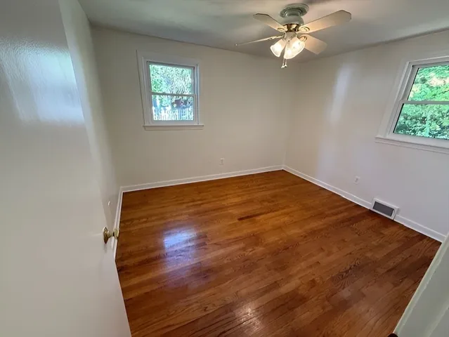 an empty room with windows and fan