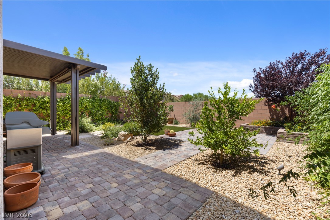 891 Earth Luster Road Las Vegas, NV 89178 - Photo 32 of 48 A spacious backyard features a paver patio with a covered outdoor grill and landscaped garden areas.
