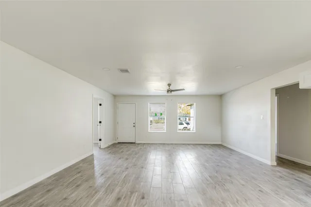 an empty room with wooden floor and windows