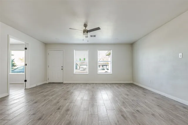a view of an empty room with wooden floor and a window