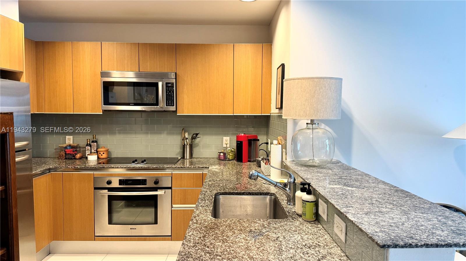 1050 Brickell Avenue, Unit 3206 Miami, FL 33131 - Photo 6 of 13 a kitchen with stainless steel appliances granite countertop a stove a sink and a microwave