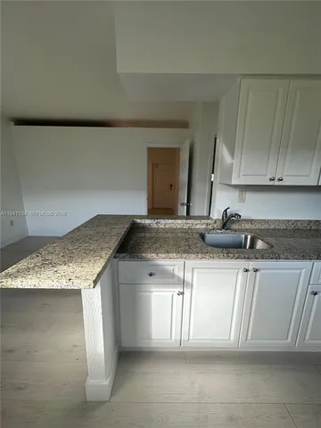 a kitchen with granite countertop sink and cabinets