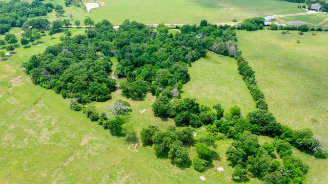 an aerial view of residential houses with outdoor space and trees all around