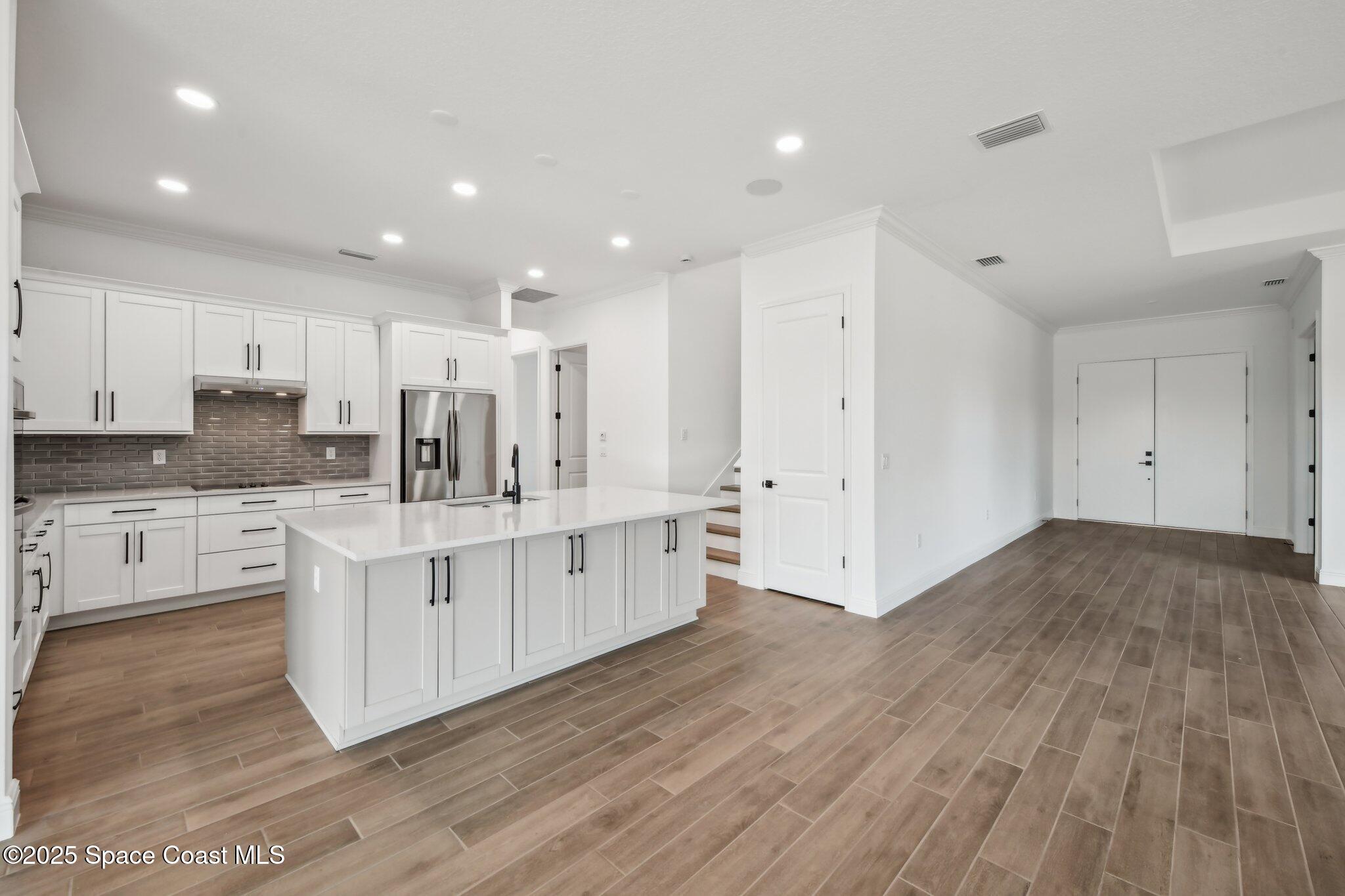 1405 Windchime Lane Melbourne, FL 32935 - Photo 16 of 48 a kitchen with stainless steel appliances granite countertop a stove a sink and white cabinets with wooden floor