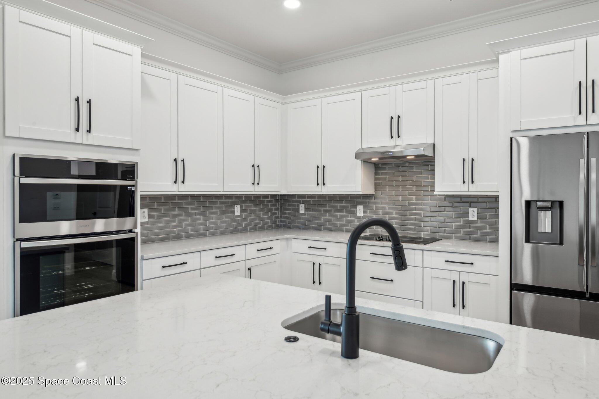 1405 Windchime Lane Melbourne, FL 32935 - Photo 18 of 48 a kitchen with granite countertop white cabinets and stainless steel appliances