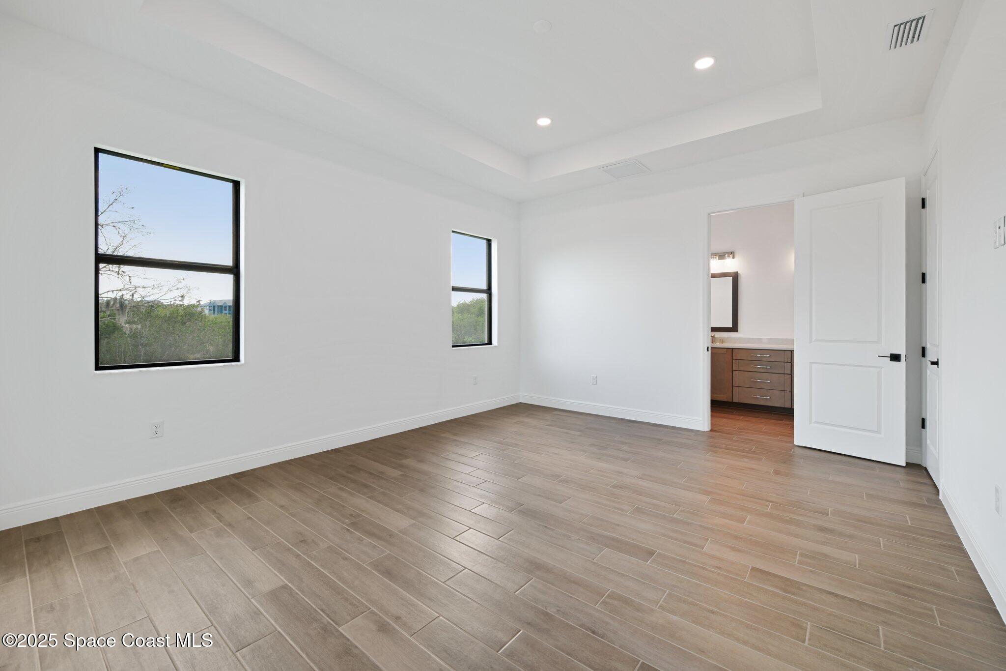 1405 Windchime Lane Melbourne, FL 32935 - Photo 21 of 48 an empty room with wooden floor and windows