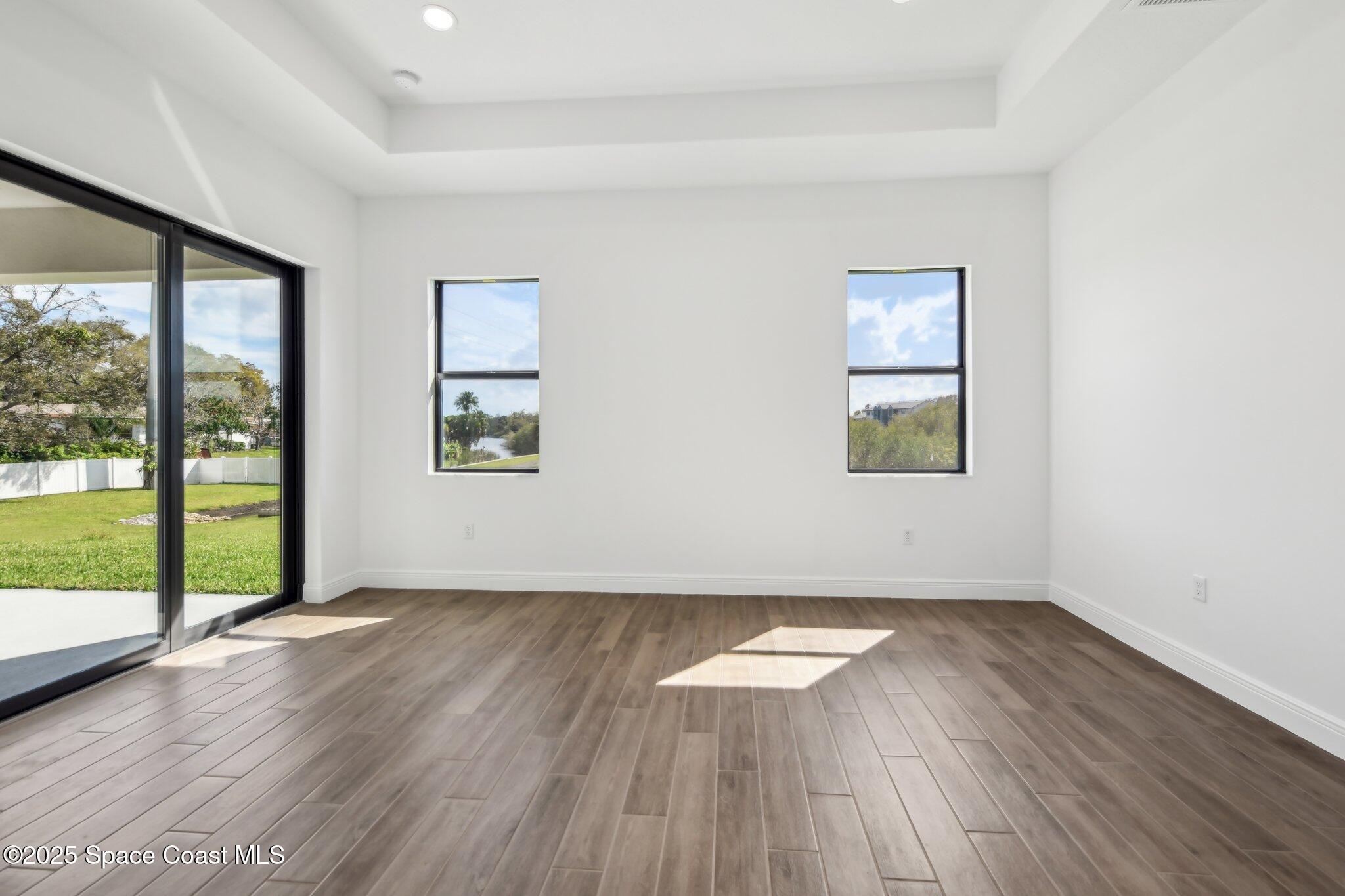 1405 Windchime Lane Melbourne, FL 32935 - Photo 22 of 48 an empty room with wooden floor and windows