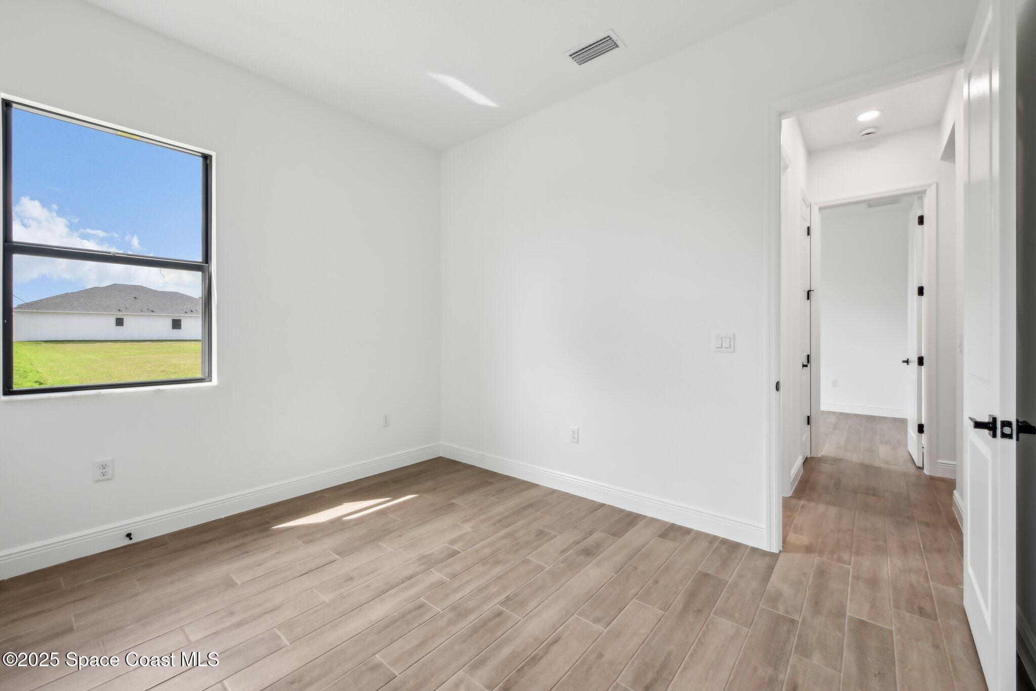1405 Windchime Lane Melbourne, FL 32935 - Photo 27 of 48 a view of an empty room with wooden floor and painting on the wall