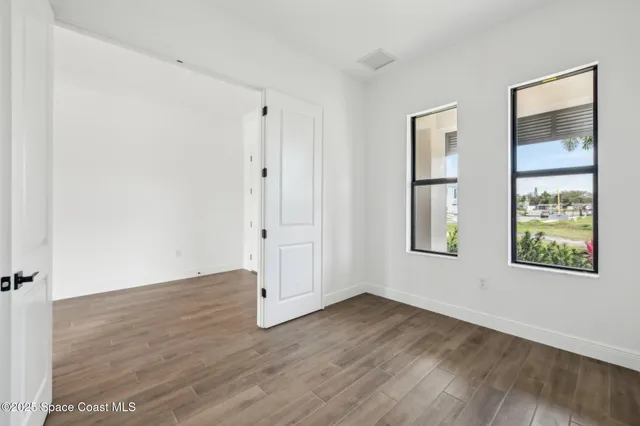 an empty room with wooden floor and windows