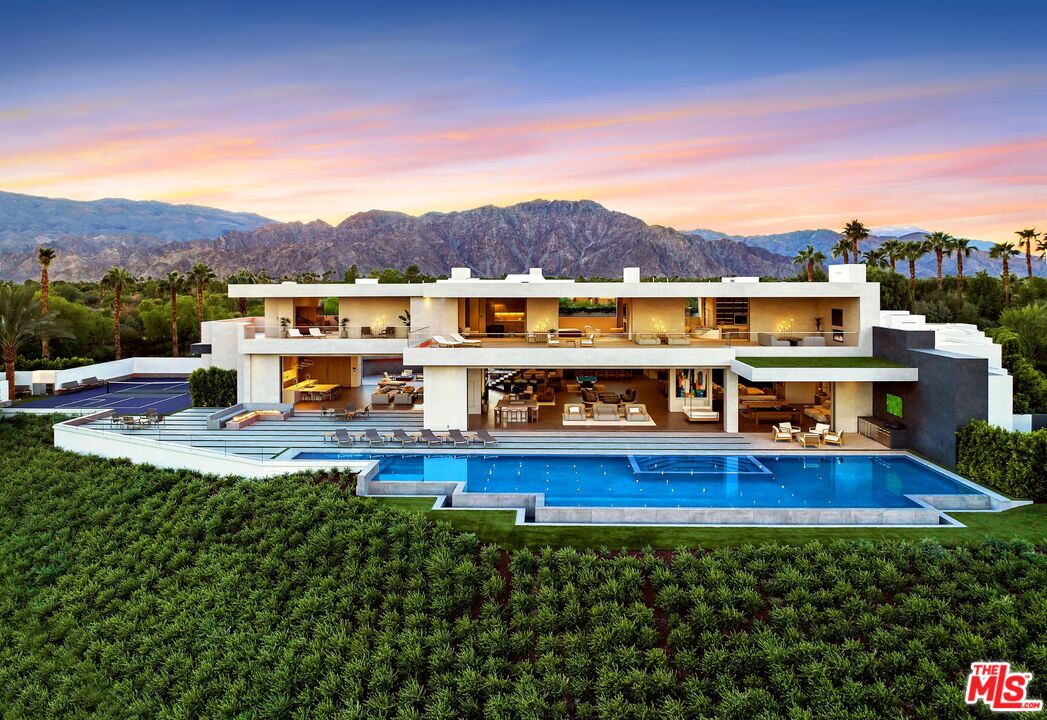 a view of a swimming pool with lawn chairs and large trees