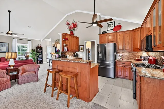 a kitchen with stainless steel appliances granite countertop a refrigerator a sink dishwasher a stove and a dining table with the kitchen view