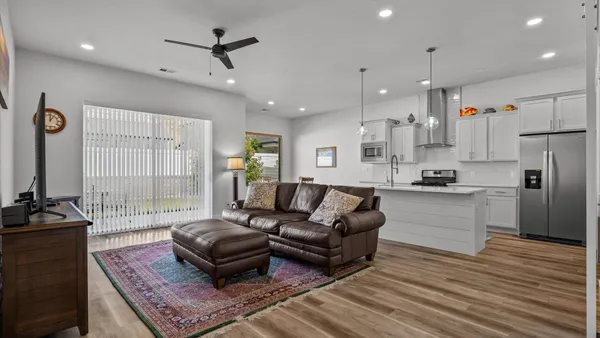 a living room with furniture kitchen and a wooden floor