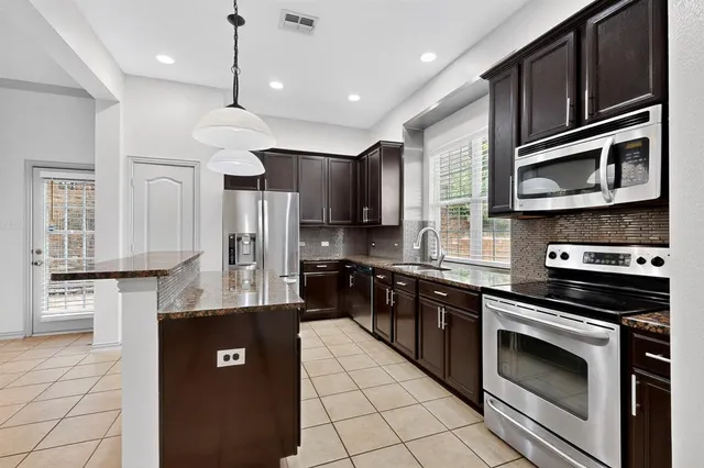 a kitchen with stainless steel appliances granite countertop a stove a sink and a refrigerator