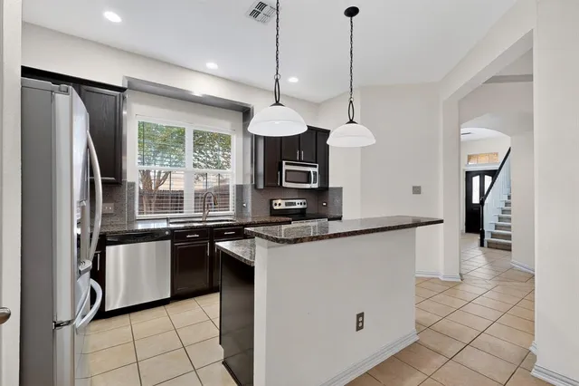 a kitchen with stainless steel appliances granite countertop a refrigerator a sink a stove and a refrigerator