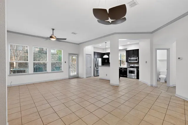 a view of an empty room with a window and kitchen view