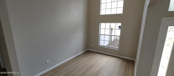 an empty room with wooden floor and windows