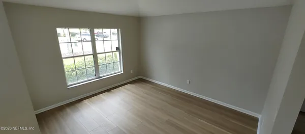 an empty room with wooden floor and windows