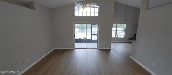 an empty room with wooden floor and windows