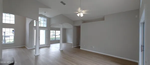 a view of an empty room with wooden floor and a window