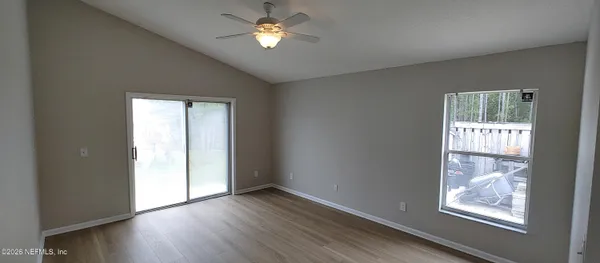 a view of an empty room with a window and wooden floor