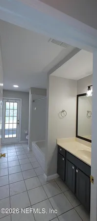 a spacious bathroom with a granite countertop sink a mirror and a bathtub