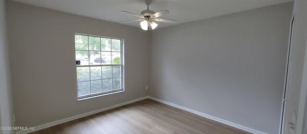an empty room with windows and fan