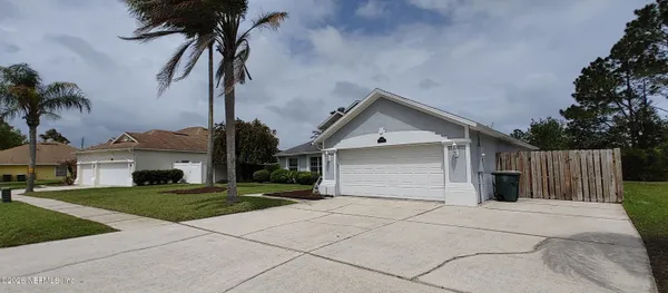 a view of a house with a yard and palm trees