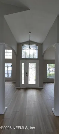 a view of an empty room with wooden floor and windows