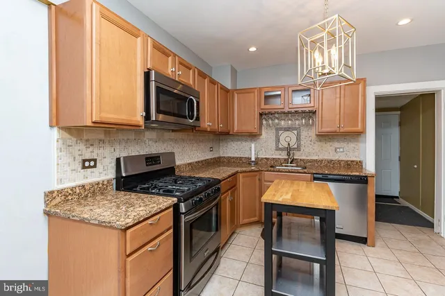 a kitchen with granite countertop a stove top oven a sink dishwasher and cabinets with wooden floor