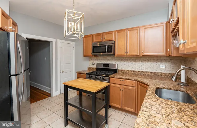 a kitchen with stainless steel appliances granite countertop a stove refrigerator sink and microwave