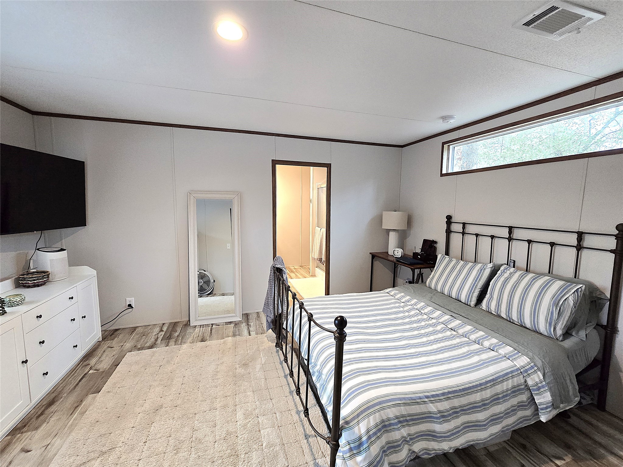 20 Morris Creek Road Coldspring, TX 77331 - Photo 6 of 29 This cozy bedroom features large window for natural light, and wood-style flooring. The room connects to a bathroom, enhancing convenience.
