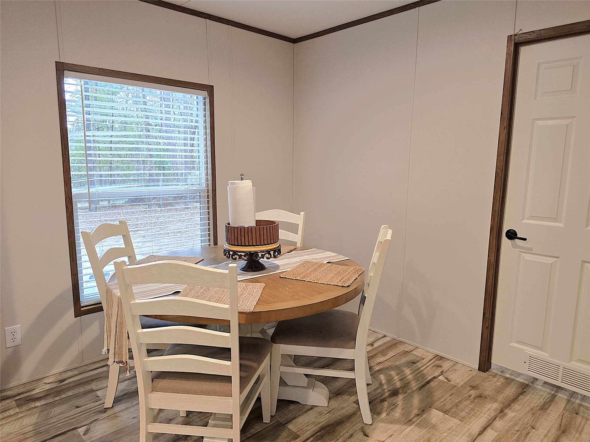 20 Morris Creek Road Coldspring, TX 77331 - Photo 9 of 29 This cozy dining area features a round wooden table with four chairs, set on light wood flooring. A large window allows natural light, creating a bright and inviting atmosphere.