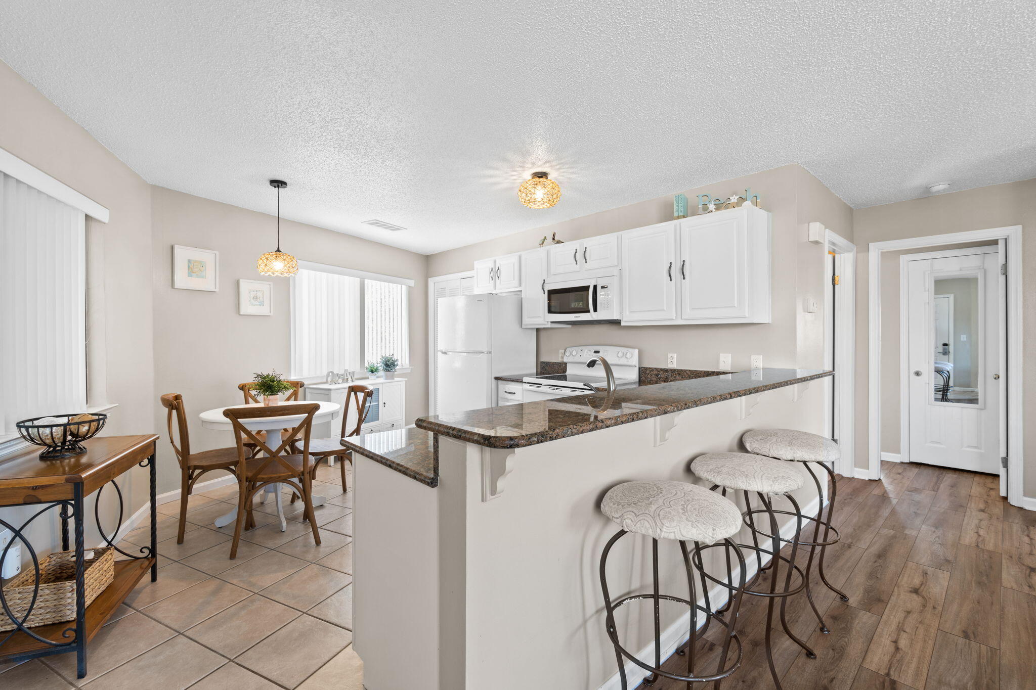 285 Payne Street, Unit 23B Miramar Beach, FL 32550 - Photo 26 of 41 a kitchen with stainless steel appliances granite countertop a table chairs stove and white cabinets