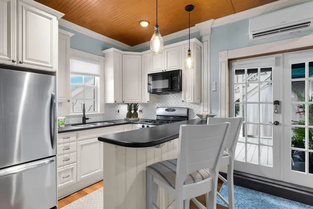 a kitchen with stainless steel appliances granite countertop a refrigerator a sink dishwasher a dining table and chairs with wooden floor