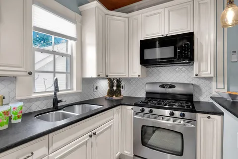 a kitchen with stainless steel appliances granite countertop white cabinets a sink and a stove