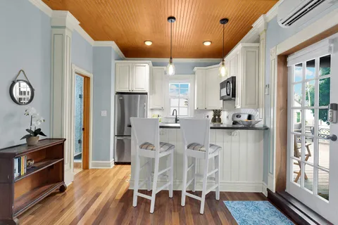 a kitchen with stainless steel appliances kitchen island granite countertop a refrigerator a stove top oven and a dining table with wooden floor