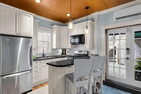 a kitchen with stainless steel appliances granite countertop a refrigerator a sink dishwasher a dining table and chairs with wooden floor