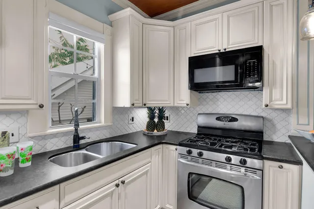 a kitchen with stainless steel appliances granite countertop white cabinets a stove a sink and a microwave