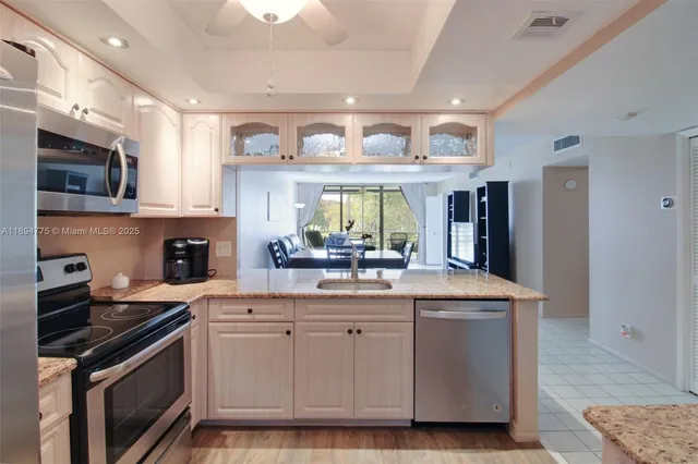 a kitchen with kitchen island granite countertop a sink cabinets and stainless steel appliances
