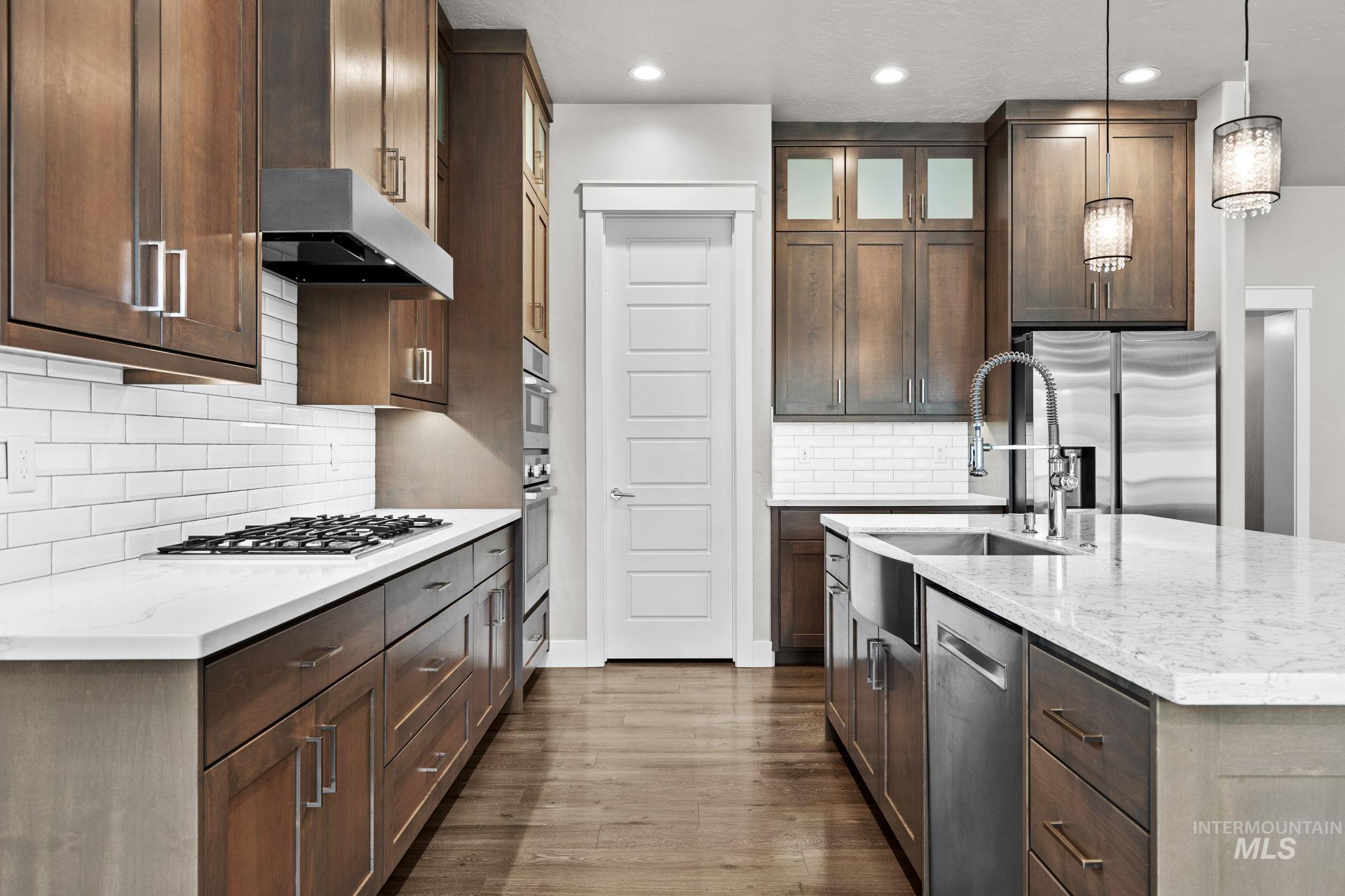 2934 East Murchison Street Meridian, ID 83642 - Photo 11 of 44 Modern kitchen featuring wood cabinetry, white subway tile backsplash, and light-toned countertops