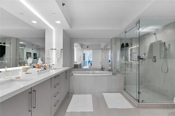 a large white bathroom with a double vanity sink mirror and shower