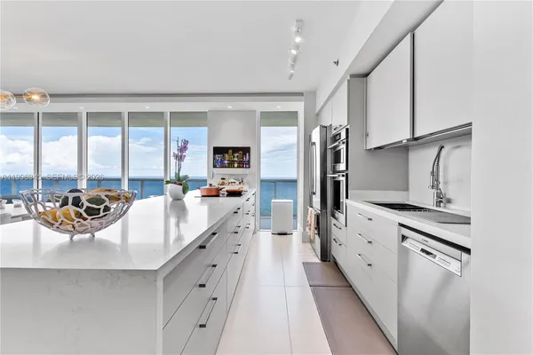 a large white kitchen with a large window and stainless steel appliances