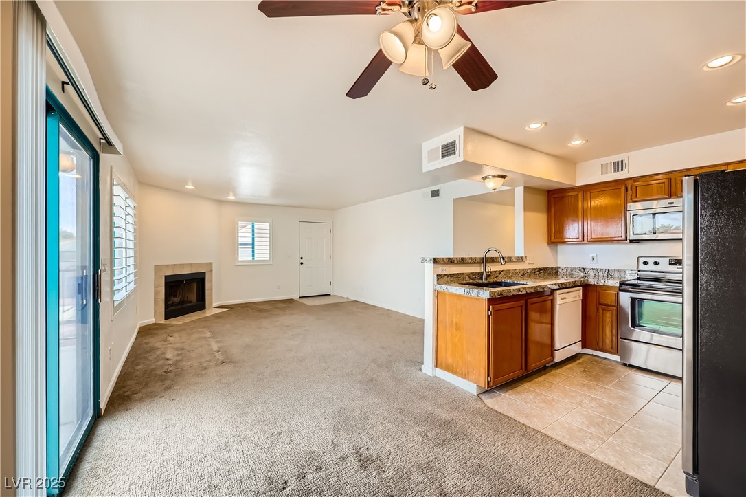 1575 West Warm Springs Road, Unit 1613 Henderson, NV 89014 - Photo 14 of 39 Kitchen with visible vents, a sink, appliances with stainless steel finishes, brown cabinets, and light colored carpet