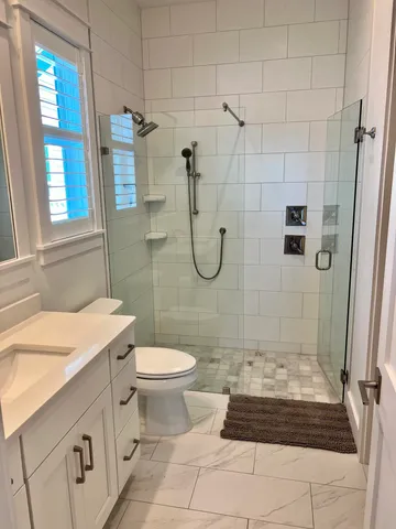 a bathroom with a granite countertop sink a toilet a mirror and shower