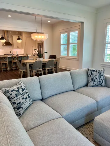 a living room with furniture kitchen view and a large window