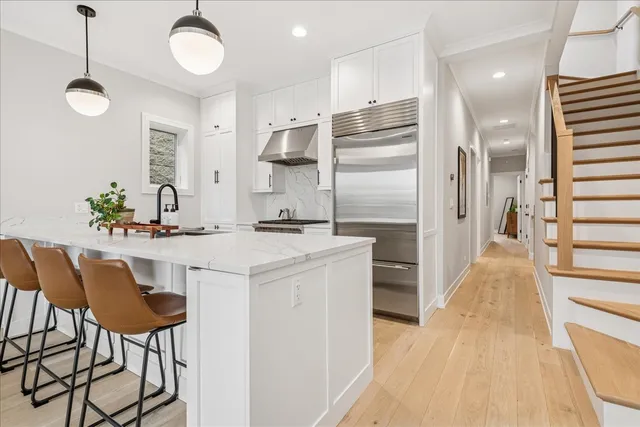 a kitchen with stainless steel appliances a dining table chairs and wooden floor