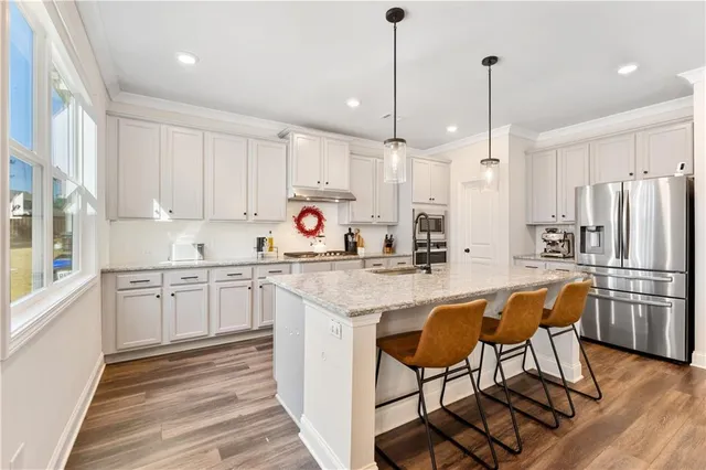 a kitchen with stainless steel appliances granite countertop a sink a stove a refrigerator and island with wooden floor