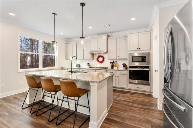 a kitchen with stainless steel appliances granite countertop a sink a stove a refrigerator and island with wooden floor