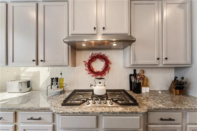 a kitchen with stainless steel appliances granite countertop white cabinets and a stove