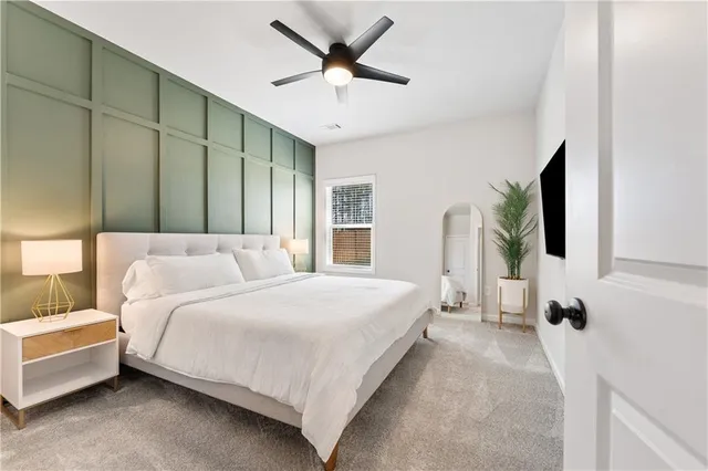 a spacious bedroom with a bed a window and a flat screen television